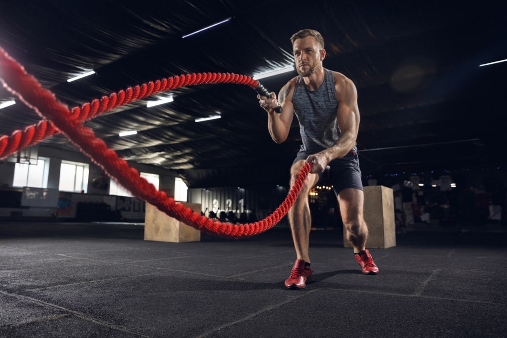 Healthy young man, athlete doing exercise with the ropes in the gym