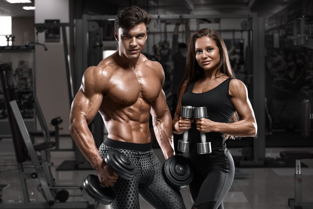 Sporty sexy couple showing muscle and workout in gym.