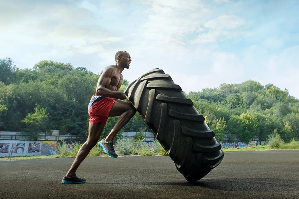 muscular man flipping the big tire outdoors